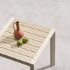 A close-up view of a wooden table with a terracotta vase and two green limes. Produktbild-Vorschau