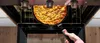 A person is using a remote control to take a flachpfanne out of an oven. Produktbild-Vorschau