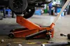 A car jack is being used to lift a car in a garage or workshop. Voir les images du produit