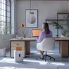 A woman is working at a desk in a modern office with a laptop and a paper shredder. Anteprima dell’immagine prodotto