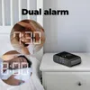 A lifestyle shot showing a digital alarm clock on a nightstand next to a bed, with inset circular images of people sleeping and digital clock displays. Podgląd zdjęcia produktu