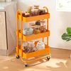 A three-tiered orange kitchen cart filled with various food items in glass jars. Podgląd zdjęcia produktu