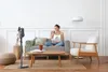 A woman is reading a book and drinking coffee on a sofa, with a vacuum cleaner in the foreground. Voir les images du produit
