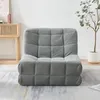A gray upholstered floor chair is shown in a room with a wooden cabinet and a plant. Náhled obrázku produktu