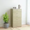 A tall, narrow chest of drawers with six drawers, made of wood-look material, stands against a white wall. A green potted plant is to the left, and a teapot and two cups sit on top of the chest. Podgląd zdjęcia produktu