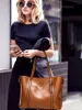A woman holding a phone and a handbag. Produktbild-Vorschau