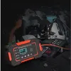 A car battery charger is shown connected to a car battery in an engine bay. Produktbild-Vorschau