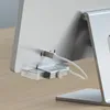A close-up view of the back of a silver computer monitor, showing a white USB-C cable plugged into a hub attached to the monitor. Produktbild-Vorschau