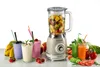 A retro-style blender is displayed with various fruit smoothies and fresh fruits and vegetables arranged around it. Produktbild-Vorschau