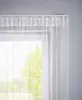 A close-up view of white string curtains hanging from a curtain rod. Produktbild-Vorschau