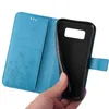 A hand holding a blue flip phone case with a floral and butterfly design. Produktbild-Vorschau
