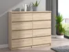 A light brown wooden dresser with eight drawers is shown in a room with a window and plants. Produktbild-Vorschau