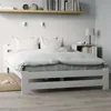A white wooden bed with a checkered duvet and pillows. Produktbild-Vorschau
