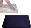 A person's feet stepping onto a beige bath mat with soap suds, and a separate dark blue bath mat. Produktbild-Vorschau
