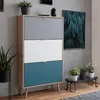 A modern shoe cabinet with three drawers in different colors, placed in a room with a concrete wall and wooden floor. Produktbild-Vorschau