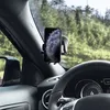 A smartphone mounted on a car dashboard using a suction cup holder, with a view of trees and a road through the windshield. Produktbild-Vorschau
