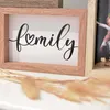 A close-up of a wooden picture frame with the word 'family' written in script, next to another picture frame with a child in it. Dried flowers are in the foreground. Náhled obrázku produktu
