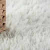 A close-up of a fluffy white rug with a woven brown basket edge. Produktbild-Vorschau