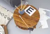 A round wooden coffee table with art supplies and canvases on it, next to a rug and a sofa. Voir les images du produit