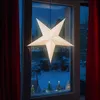 A lit star decoration hangs in a window at night, with a snowy scene visible outside. Anteprima dell’immagine prodotto