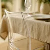 A close-up of a transparent chair at a dining table set for a meal. Produktbild-Vorschau