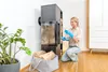 A woman is cleaning a wood-burning stove with a cleaning product. Produktbild-Vorschau