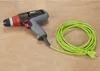 A corded electric drill is placed on a wooden surface next to its coiled green power cord. Podgląd zdjęcia produktu