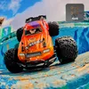 An orange remote-controlled off-road car is positioned on a colorful, textured surface, possibly a ramp or obstacle course, with a blue sky and clouds in the background. Anteprima dell’immagine prodotto