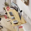 A modern height-adjustable desk with dual monitors, a laptop, and office supplies, shown in a bright room with wooden flooring. Podgląd zdjęcia produktu