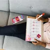 A person is lying on a couch, marking a calendar with a red marker. Produktbild-Vorschau