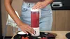 A person is using a portable blender to make a smoothie in a kitchen setting. Podgląd zdjęcia produktu