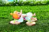 A doll is lying on a miniature lounge chair in a grassy outdoor setting. Produktbild-Vorschau