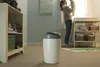A nursery room with a mother holding a baby near a changing table, with a diaper pail in the foreground. Voir les images du produit