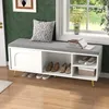 A white shoe bench with a gray cushion and storage compartments is placed in a hallway or living room setting, next to a window with greenery visible outside. Produktbild-Vorschau