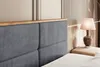 A close-up view of a bed's headboard and a bedside table with a lamp. Produktbild-Vorschau