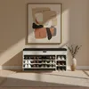 A shoe cabinet with a bench seat in a hallway, with a piece of abstract art on the wall above it. Produktbild-Vorschau