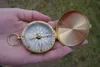 A hand holding a classic brass compass with its lid open. Produktbild-Vorschau