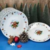Christmas-themed plates with gingerbread man designs, surrounded by miniature Christmas trees and pinecones. Náhled obrázku produktu
