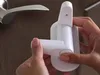 A person's hands are shown installing a white child safety lock onto a door handle. Náhled obrázku produktu