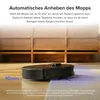 A robot vacuum cleaner is shown on a floor, approaching a rug. The background shows wooden furniture. Produktbild-Vorschau
