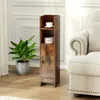 A narrow wooden cabinet with two shelves and a door, placed next to a cream-colored armchair and a potted plant. Podgląd zdjęcia produktu