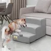 A dog is climbing on a three-step pet stair next to a sofa in a living room. Podgląd zdjęcia produktu