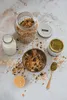 A flat lay of granola, milk, and pistachio paste, suggesting a breakfast or dessert preparation. Produktbild-Vorschau