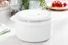 A white microwave-safe container with a transparent lid sits on a countertop. Produktbild-Vorschau