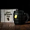 A black grenade-shaped mug with a yellow tea bag tag is displayed next to its packaging on a wooden surface. Voir les images du produit