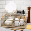 A dish drying rack filled with dishes, cups, and cutlery, placed on a countertop in front of a tiled backsplash. Náhled obrázku produktu