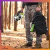 A person in camouflage clothing holding a flashlight and a backpack in a forest. Podgląd zdjęcia produktu
