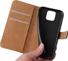 A hand holding a black phone case in front of an open brown wallet case. Produktbild-Vorschau