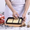 A person is using a cookie cutter to cut shapes from dough on a baking tray, with Christmas decorations in the background. Náhľad obrázku produktu