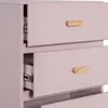 A close-up view of the drawers of a pink dresser with wooden handles. Náhled obrázku produktu